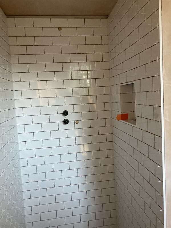 Shower walls tiled with white metro tiles