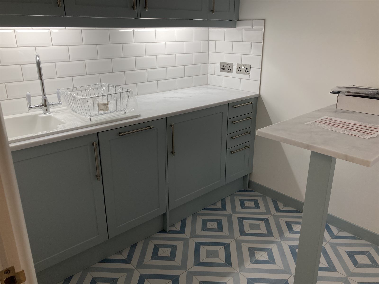 Finished kitchen with grey shaker units, marble-effect worktop and white metro tile splashback